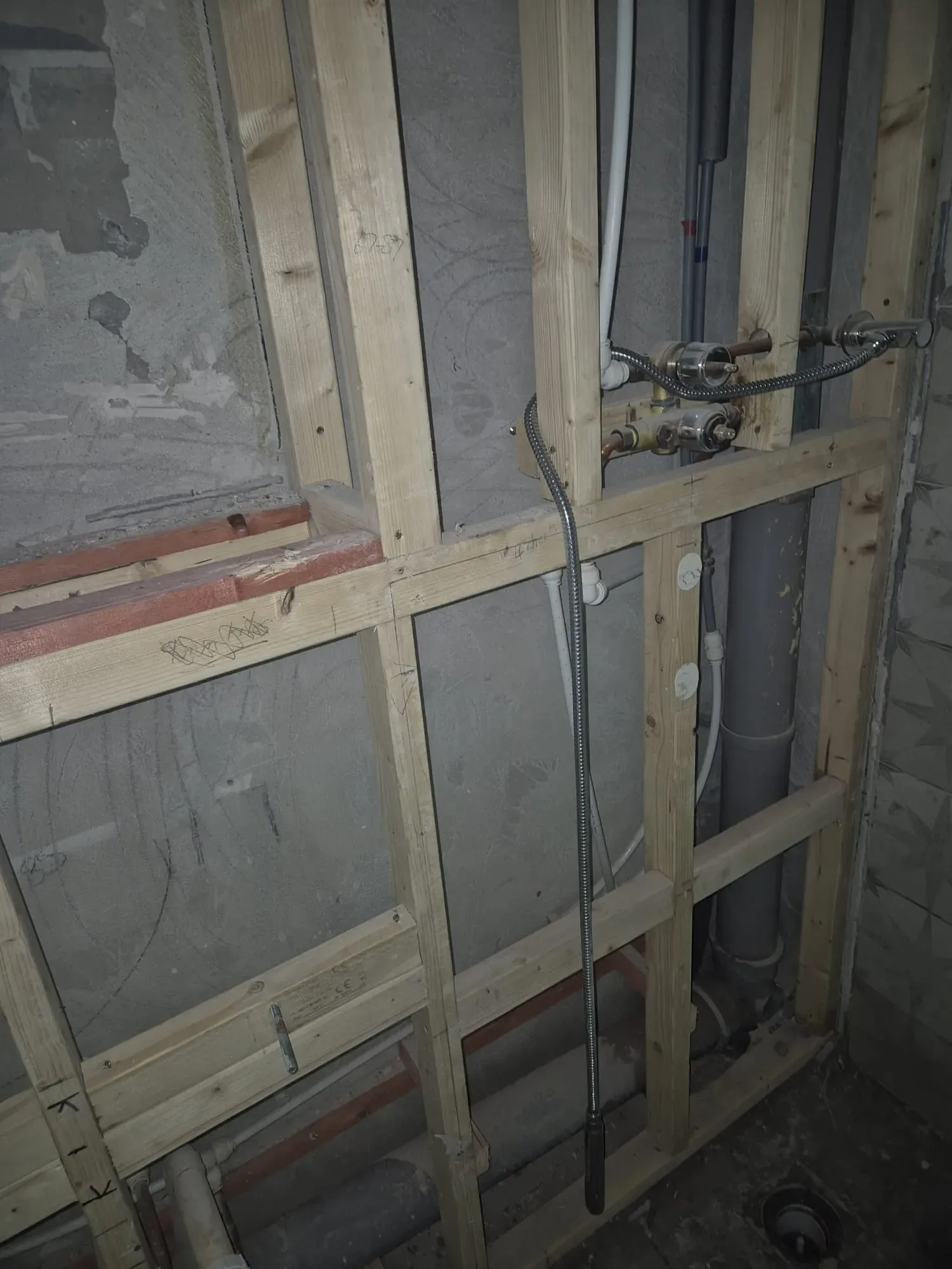 Image showing new timber stud work and concealed plumbing for a shower mixer and waste pipes in a bathroom refurbishment project.