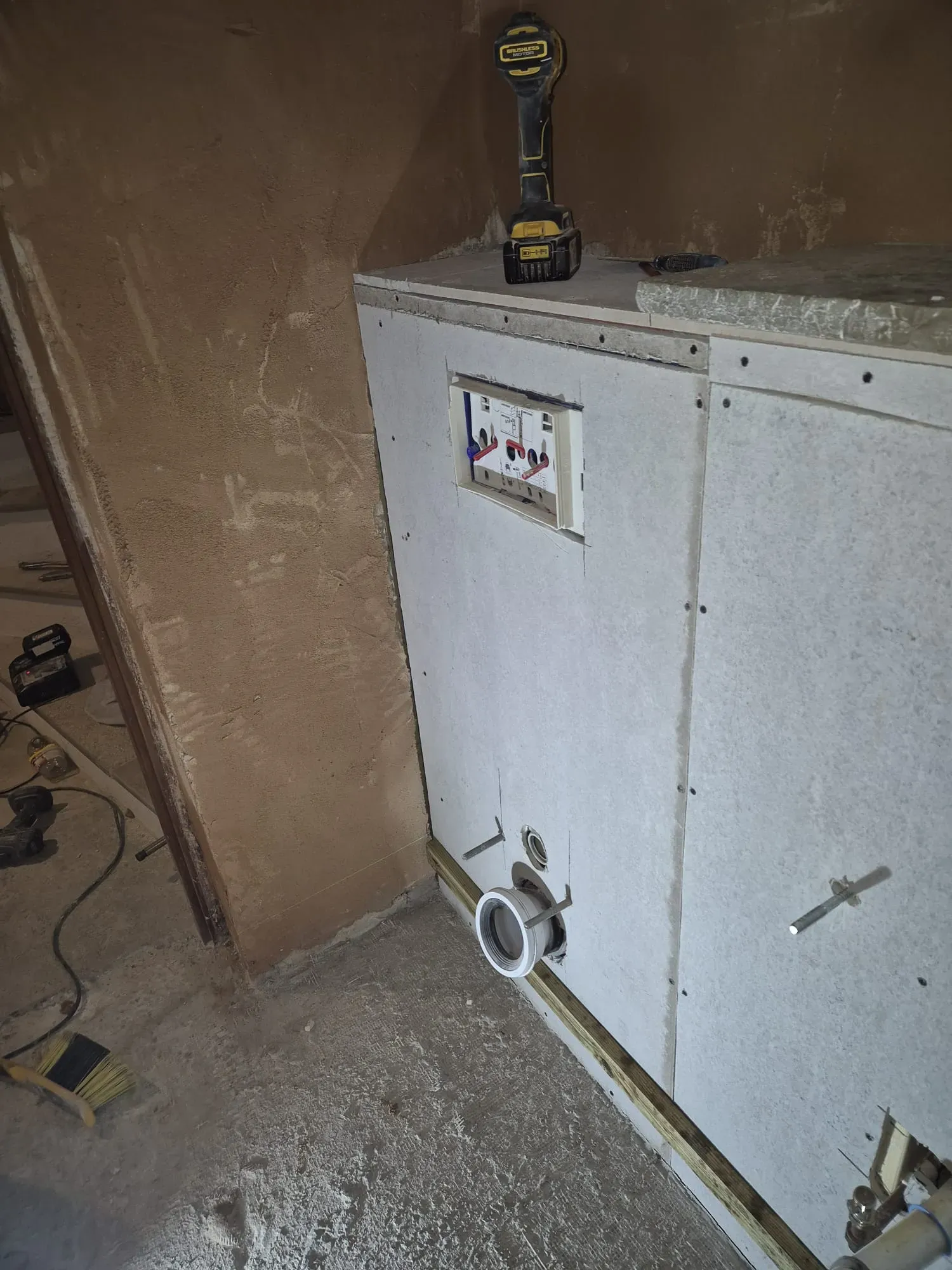 First-fix plumbing and plasterboard fitted for a wall-hung toilet during a bathroom refurbishment.